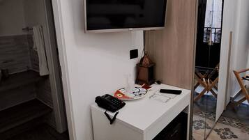 Un baño moderno con un tocador blanco, un televisor montado y un espejo.