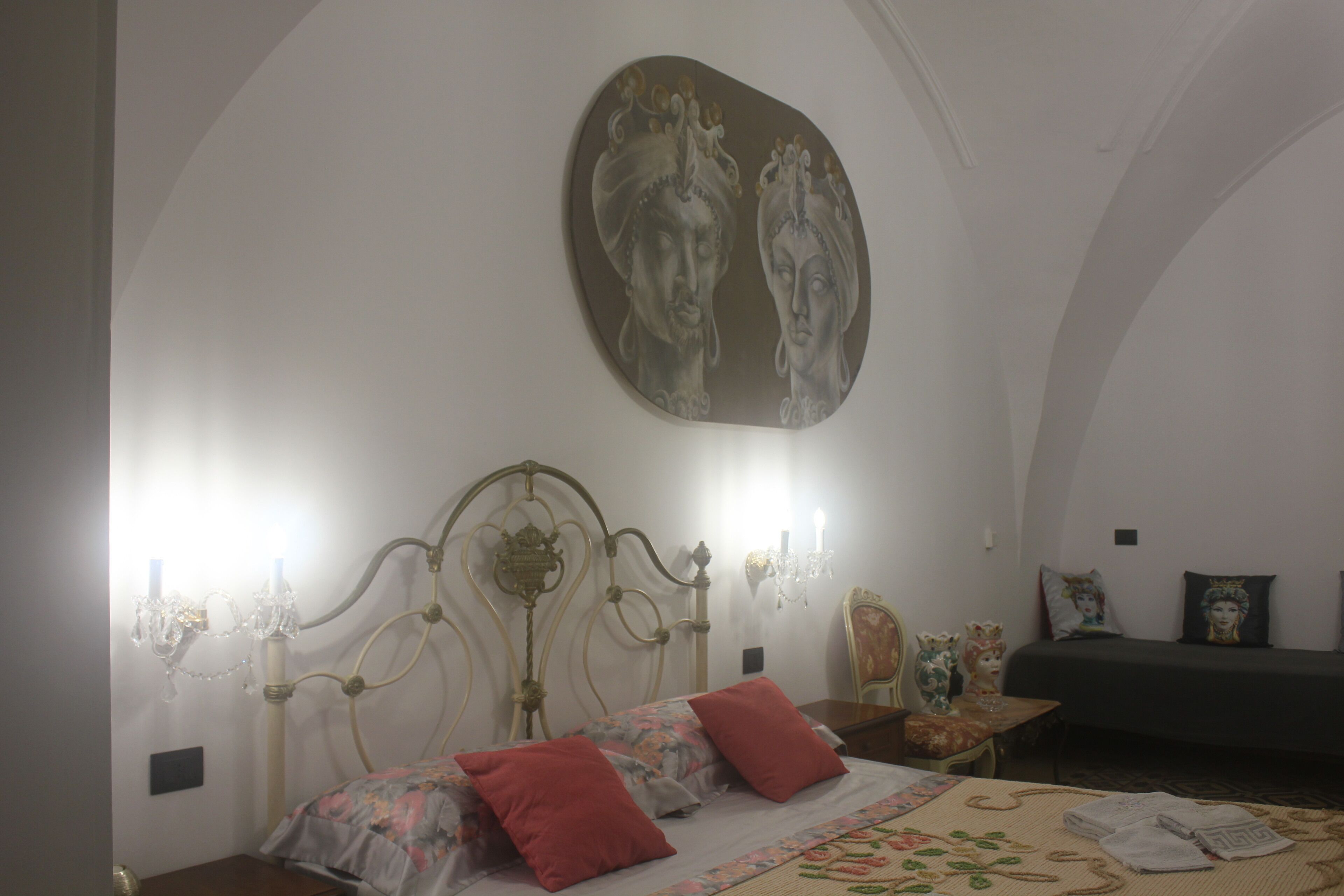 Quarto com cama, lustre, quadro e mesa de cabeceira.