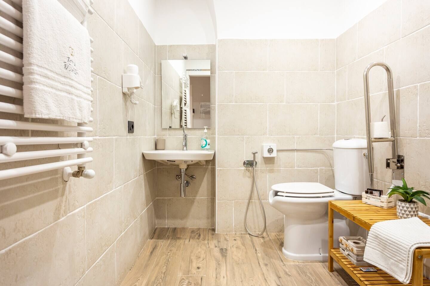 A modern bathroom with a wooden vanity, a toilet, a sink, and a towel rack.