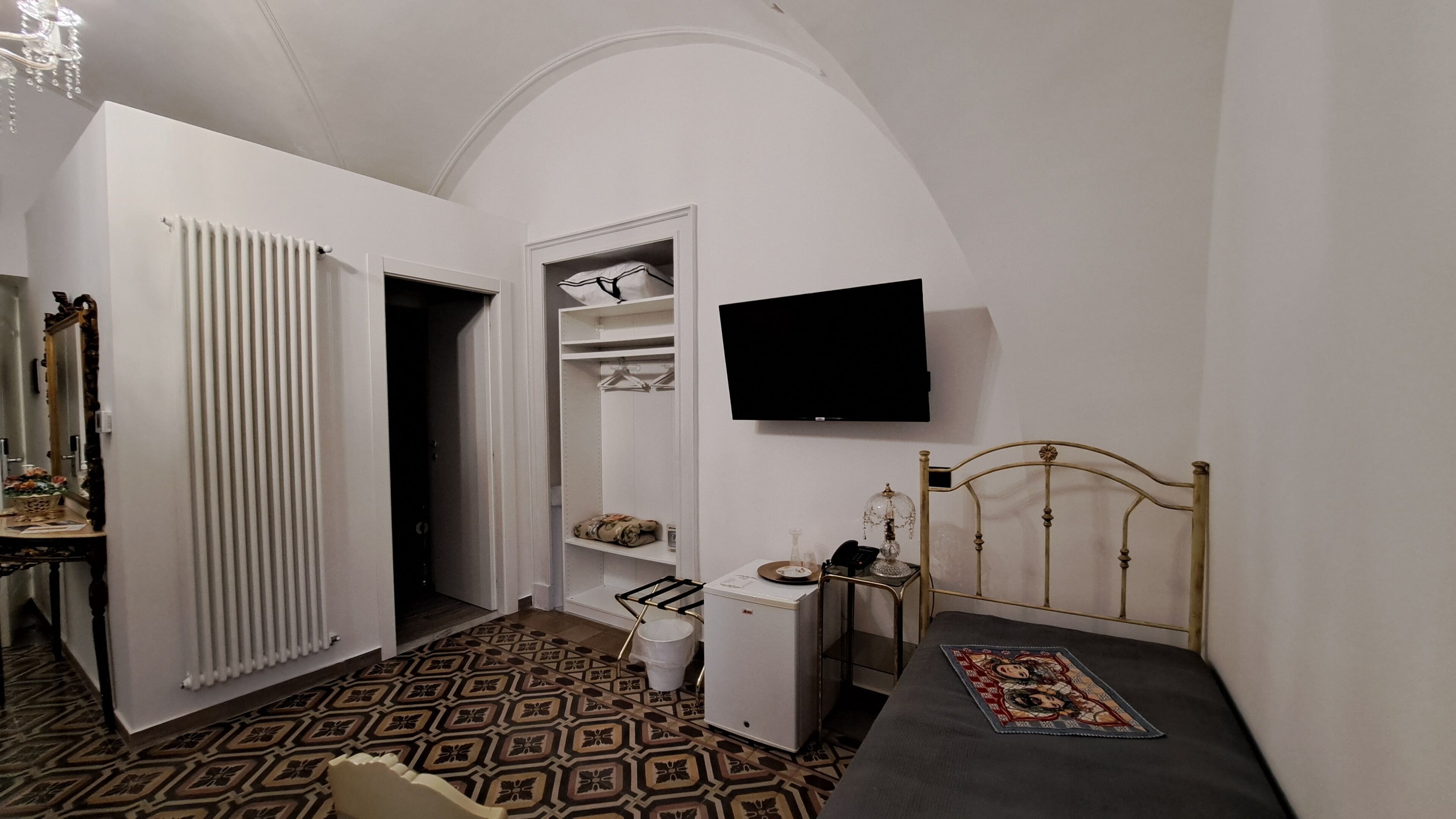 A bedroom with a bed, a television, a wardrobe, and a bathroom.