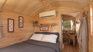 Une pièce chaleureuse, aménagée dans un chalet en bois, avec un lit, une petite kitchenette et une fenêtre.