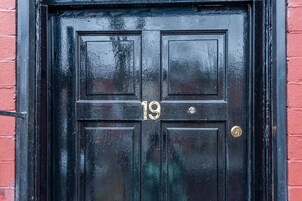 A black door with the number 19, a brass doorknob, and a brass lock.