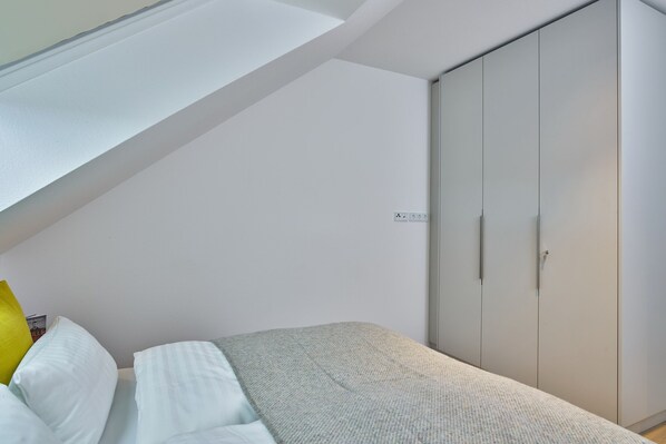 A bedroom with a bed, a wardrobe, and a skylight. - Traumferienwohnung mit 14 m² Großem Balkon und Strandkorb auf der Insel Langeoog (Langeoog)
