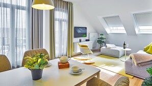 A modern living room with a dining area, a sofa, a TV, and a plant.