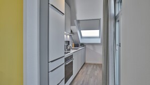 A narrow kitchen with a skylight, modern appliances, and a light-colored floor.