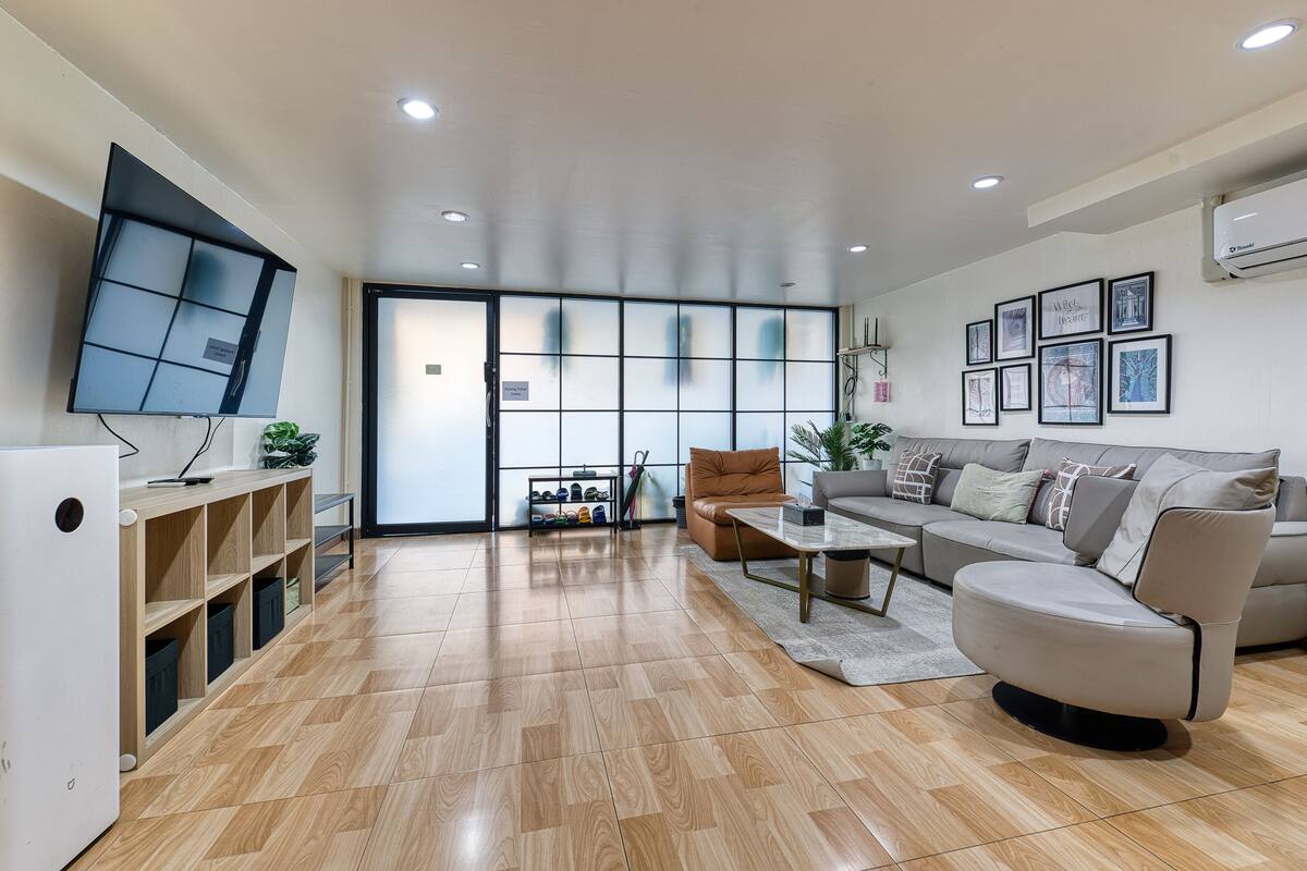 Un salon moderne comprenant un canapé, une table basse, un téléviseur et un meuble à chaussures.