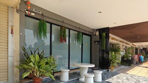 A modern building with large glass windows, outdoor seating, and potted plants.