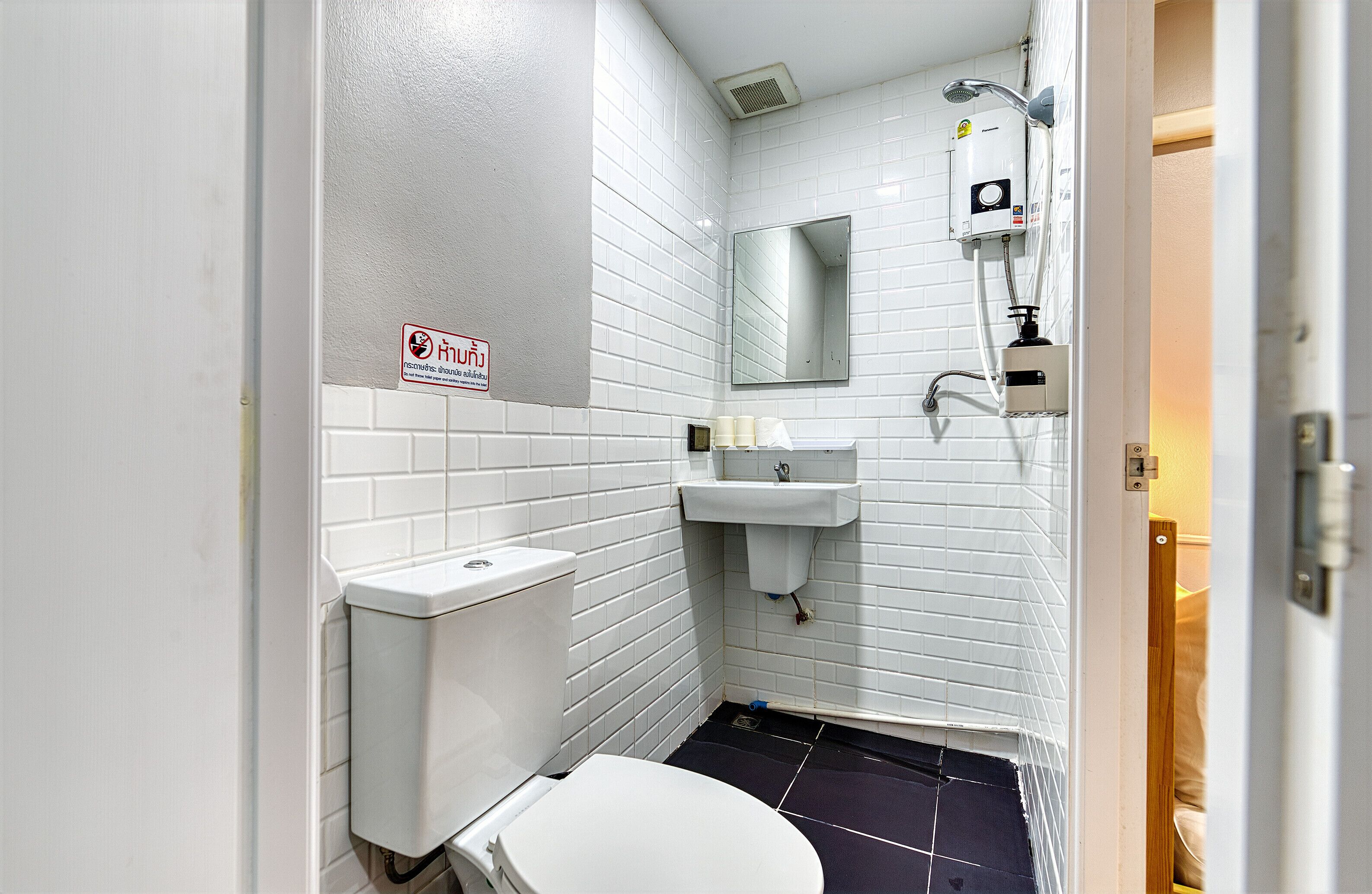 A small, white-walled bathroom with a toilet, sink, and shower.