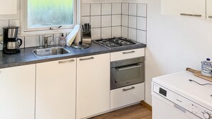 A modern kitchen with a gas stove, oven, and dishwasher. There is a window above the sink and a tiled backsplash. - Stunning (sta)caravan in Putten (Putten)