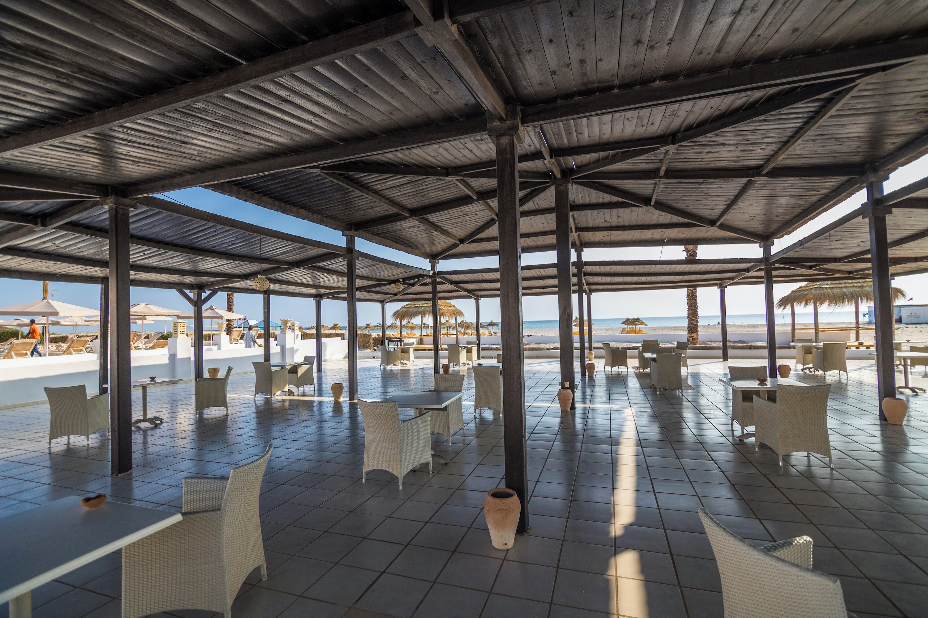 An open-air patio with tiled flooring and white wicker furniture.