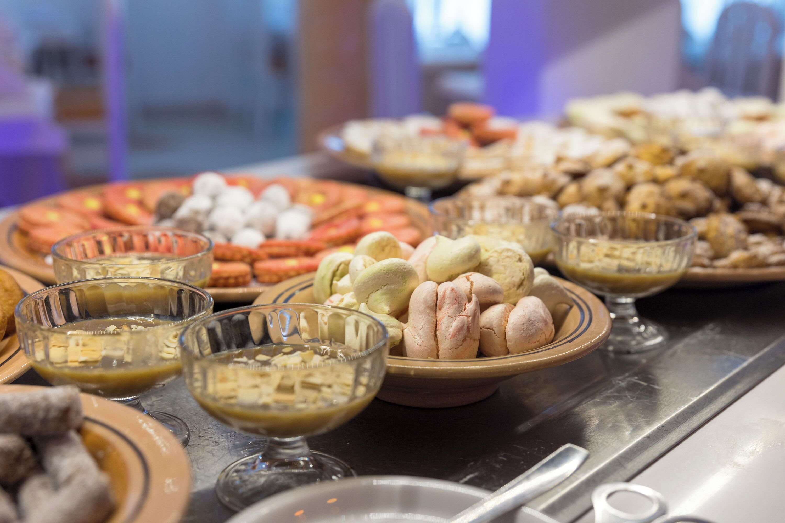 Mesa de buffet con diferentes opciones de comida, incluyendo pasteles, postres y frutas.