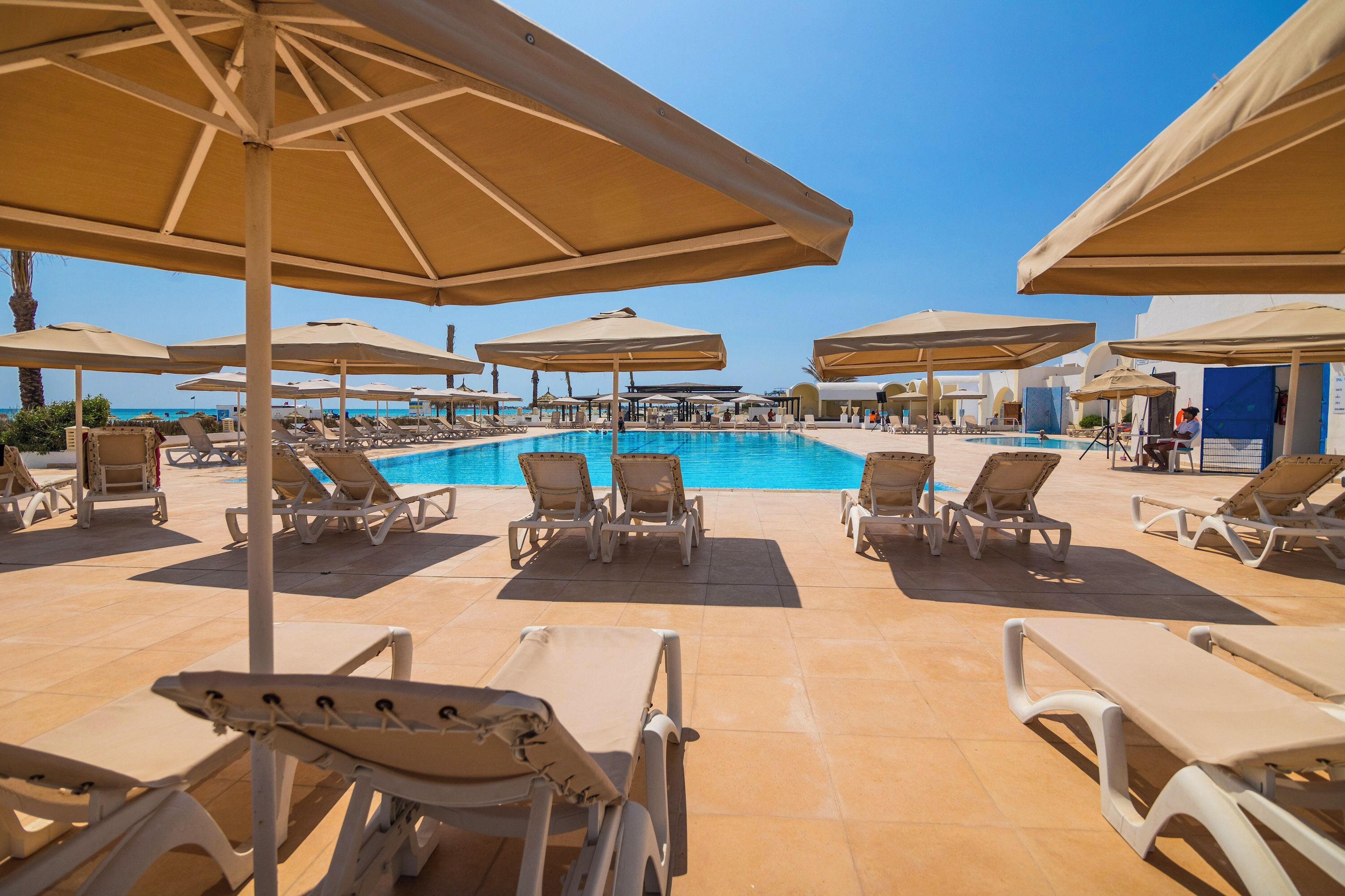 Un espace aménagé au bord de la piscine, avec des chaises longues et des parasols.