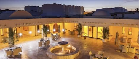 A courtyard with outdoor seating, a central water feature, and a view of the surrounding architecture.