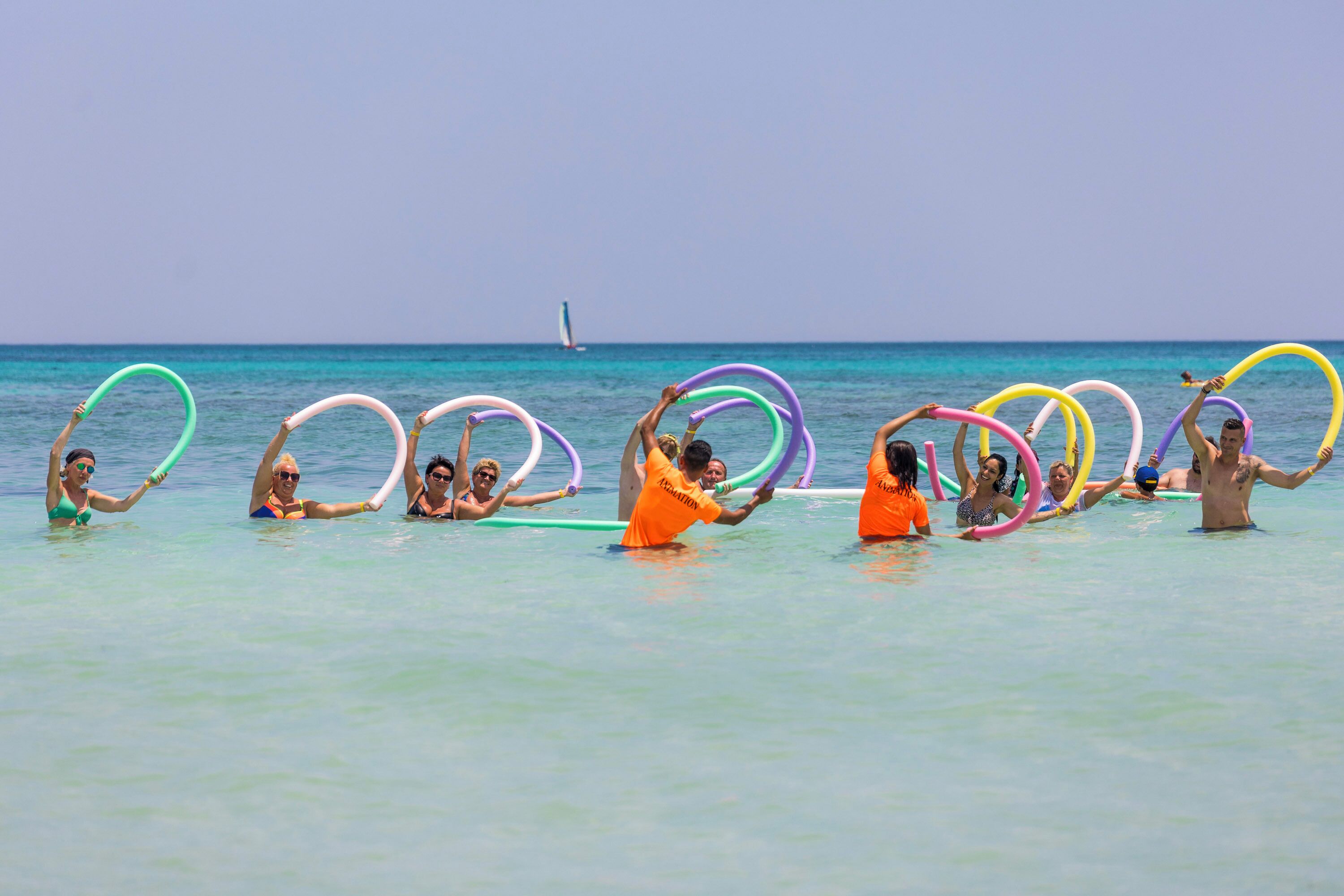 A group of people holding colorful rings in the water at the beach.