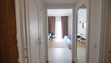 Pasillo de hotel que conduce a una habitación con cama, escritorio y silla.