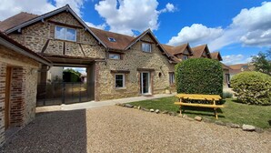 A stone house with a gravel driveway and a wooden bench. - Les Maisons du Théâtre Romain - 4 Gîtes - 10 Chambres (Le Vieil-Évreux)