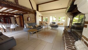 A spacious living area with a sofa, dining table, and chairs, a fireplace, and a stone wall. - Les Maisons du Théâtre Romain - 4 Gîtes - 10 Chambres (Le Vieil-Évreux)