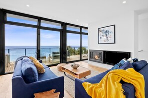A modern living room with a large window overlooking the sea, a fireplace, and a cozy seating area. - Wonder Wye (Wye River)
