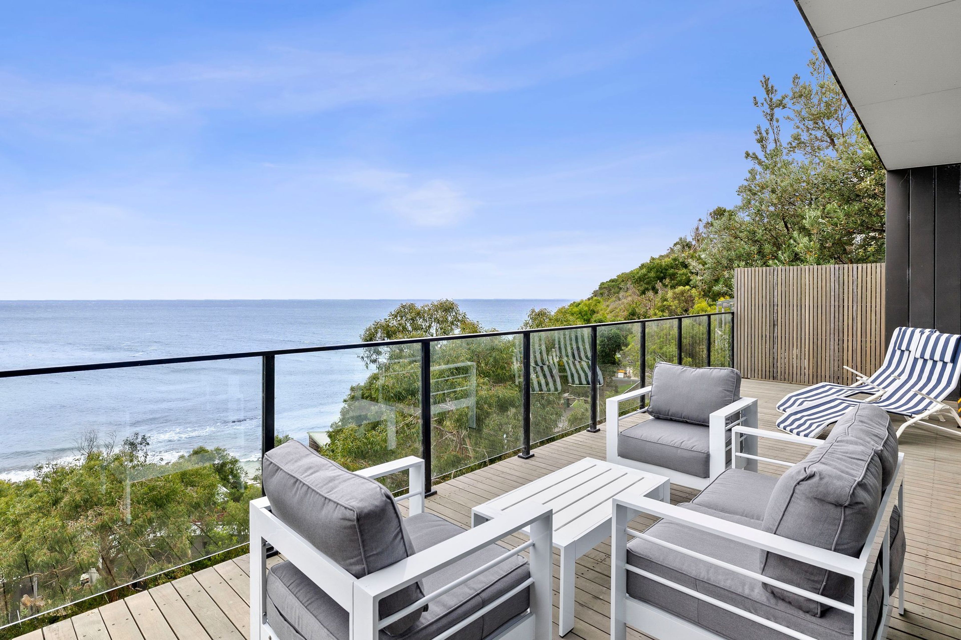 A deck with outdoor furniture overlooking a coastal view.