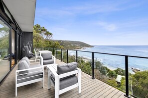 Un balcon avec des meubles blancs et une vue sur la mer.