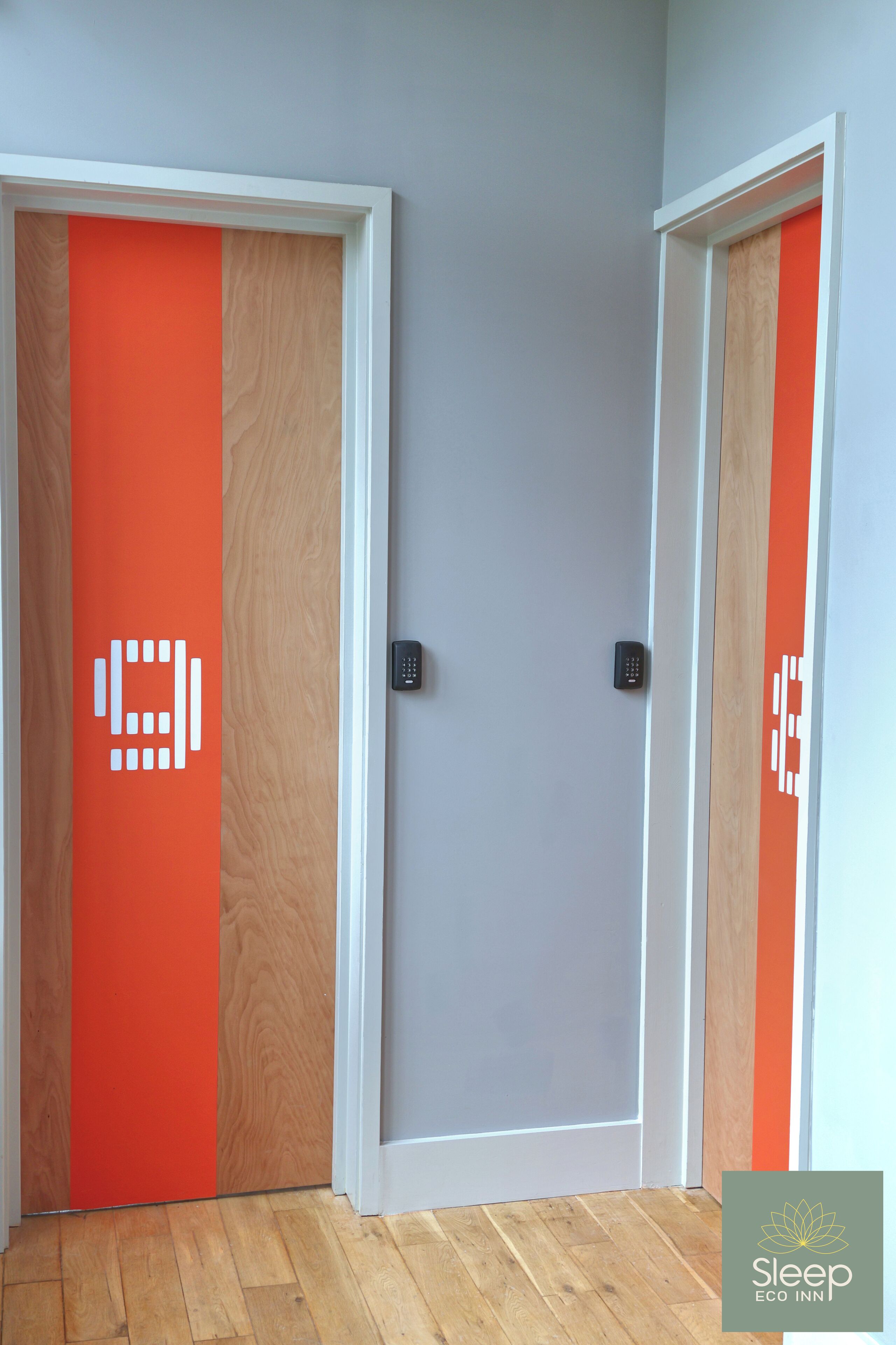 Two doors with a wooden frame and a grey wall.