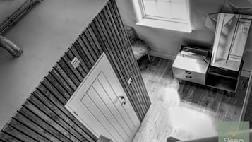 A high-angle view of a room with a wooden slatted wall, a small window, a sink, and a mirror.