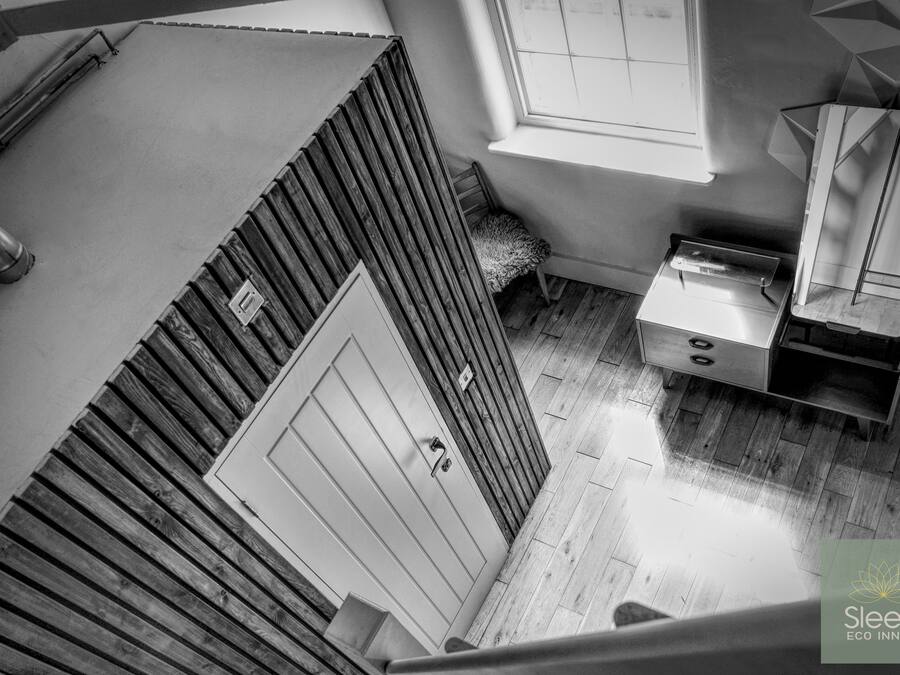 A high-angle view of a room with a wooden slatted wall, a small window, a sink, and a mirror.