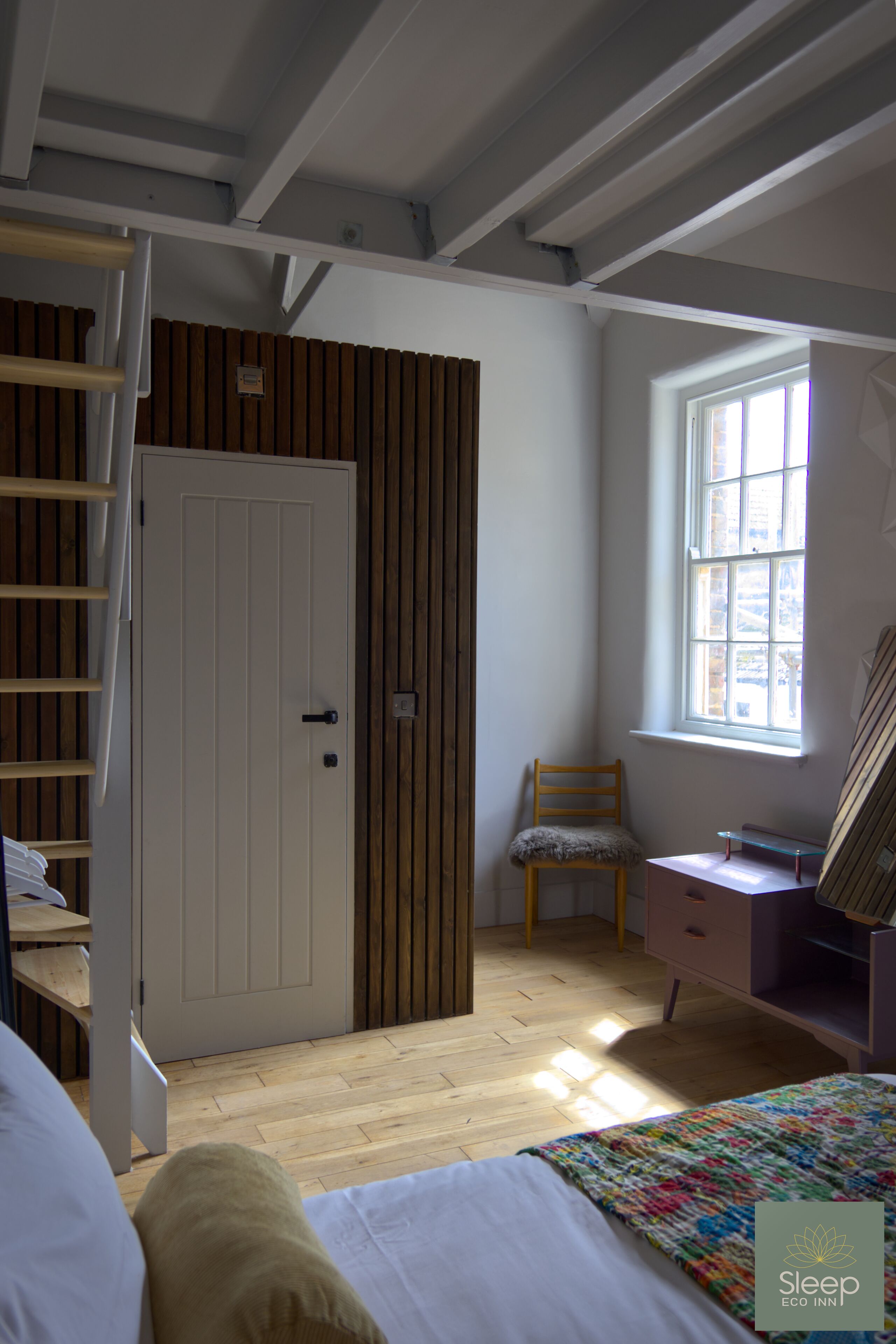 A bedroom with a bunk bed, a desk, a chair, and a window.