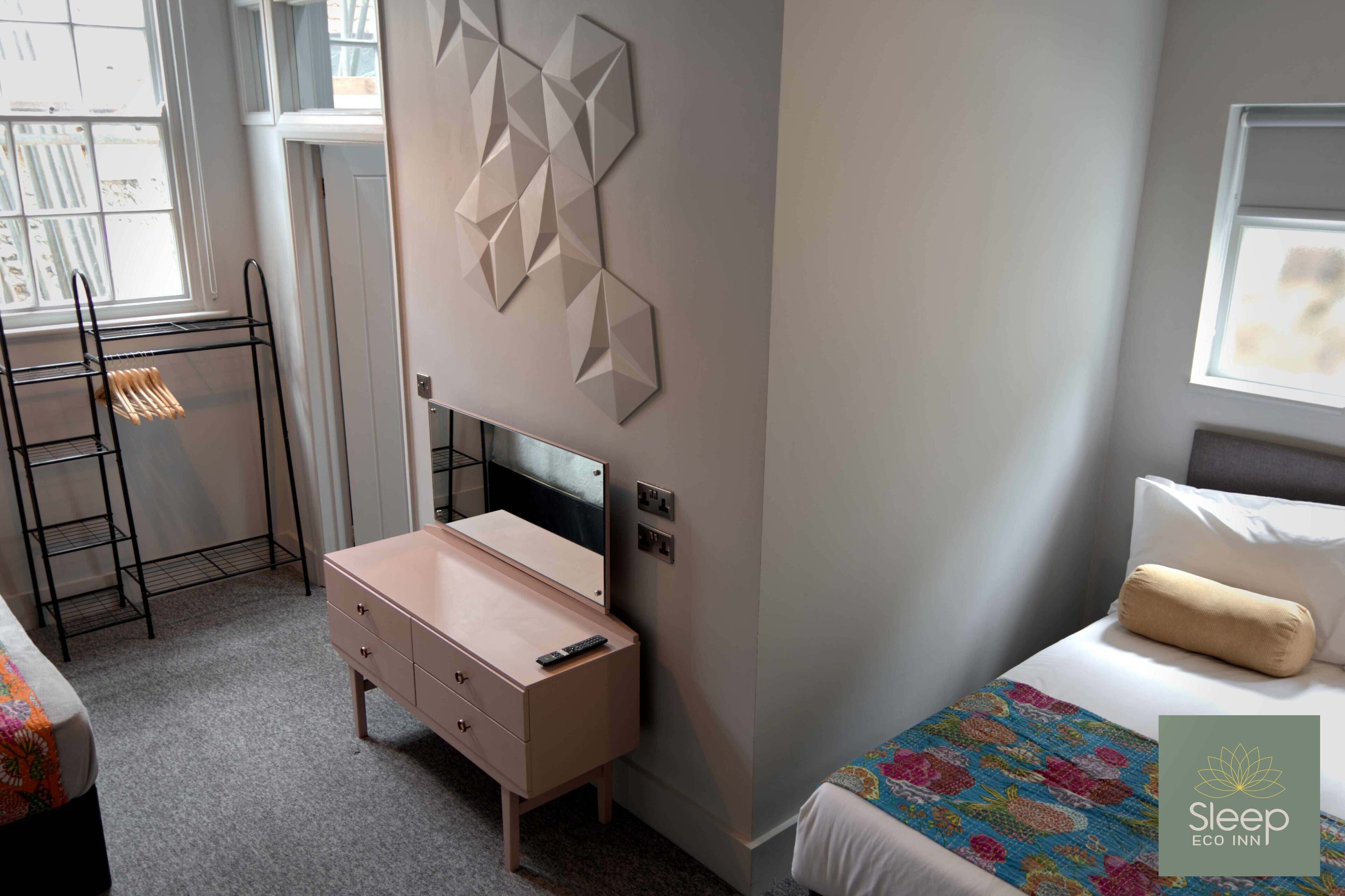 A bedroom with a bed, a dresser, a desk, and a window.