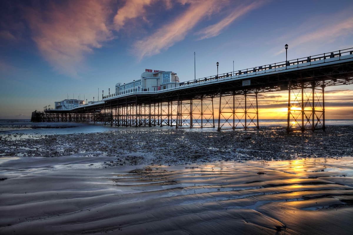 A pier extending into the water with a building on top, under a sunset sky.