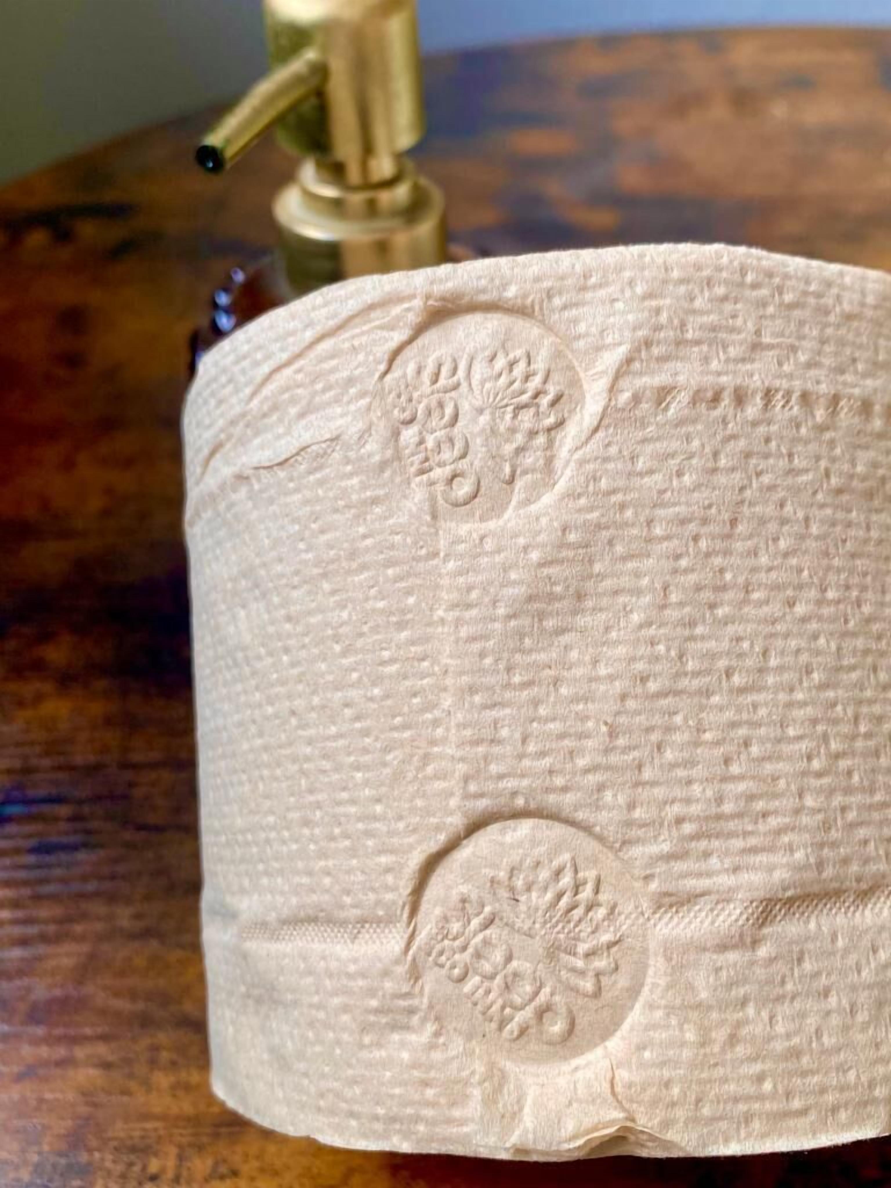 A toilet paper roll with embossed floral designs on a wooden surface.