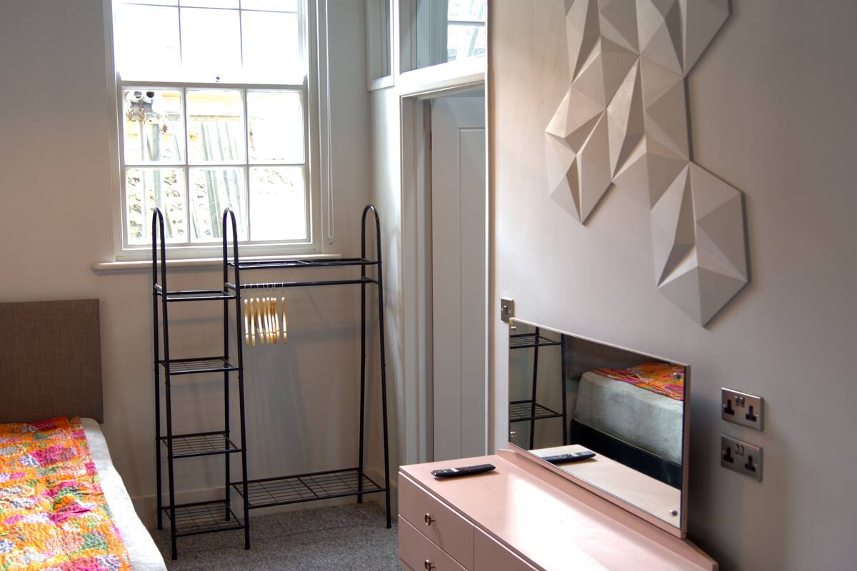 A bedroom with a bunk bed, a dresser, a mirror, and geometric wall art.