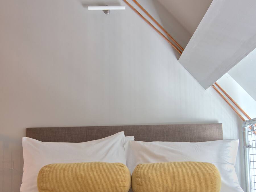 A bedroom with a bed, white bedding, a headboard, and a colorful rug.