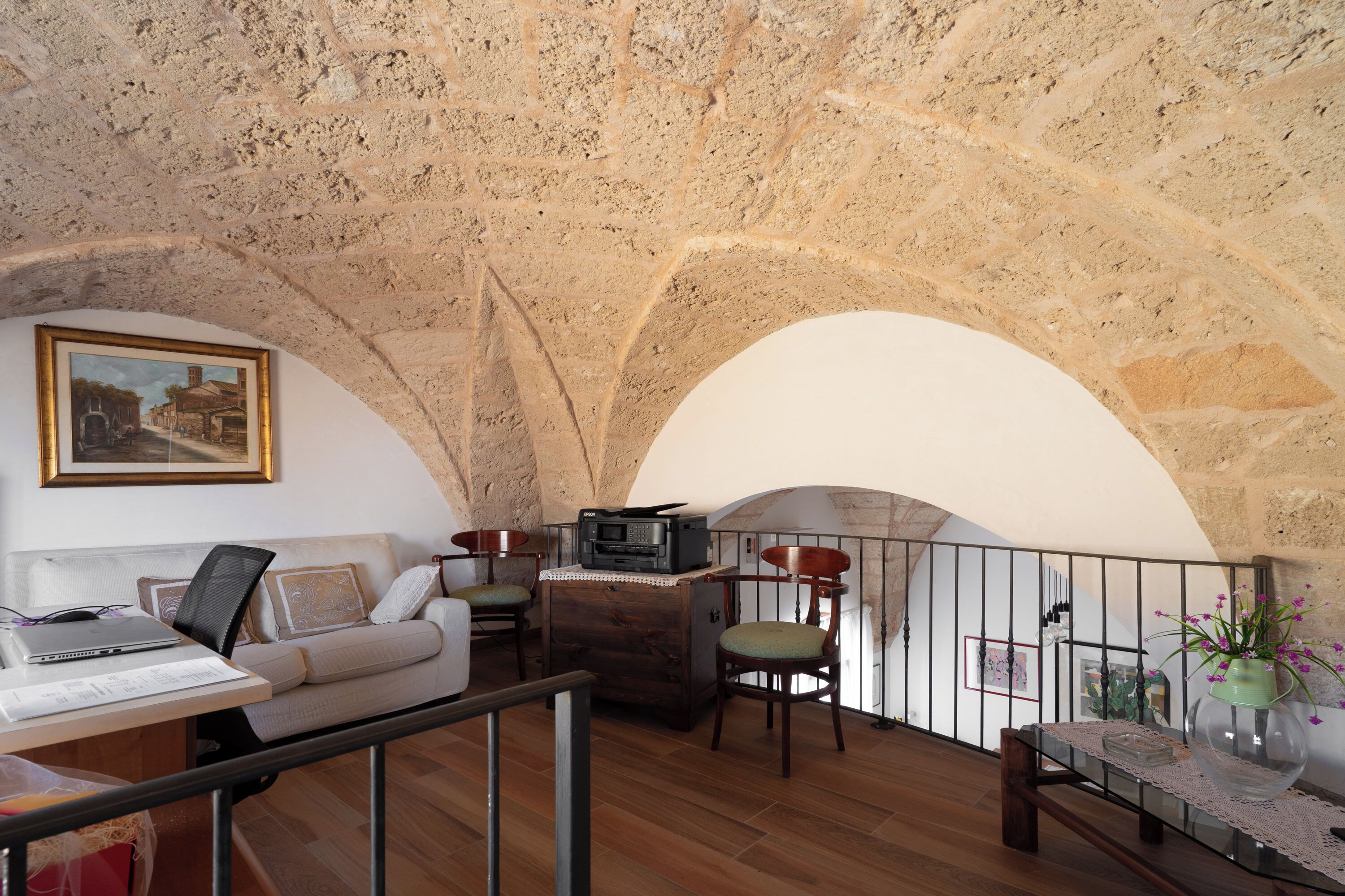 Un salon chaleureux avec un plafond en pierre, un canapé, une table basse et une table à manger avec des chaises.