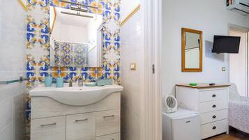 Un bagno con un lavandino bianco, uno specchio e una parete piastrellata con motivo floreale.