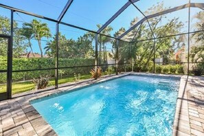 A swimming pool with a clear view of the surrounding greenery and a covered area.
