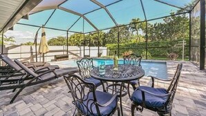 Een terras buiten met een zwembad, lounge stoelen en een tafel met stoelen.