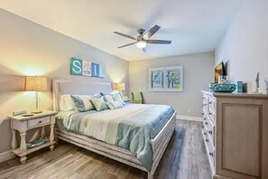 A bedroom with a bed, bedside tables, a ceiling fan, and a dresser.