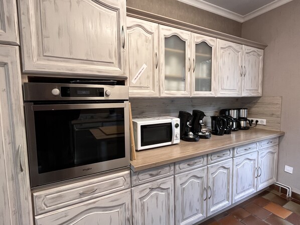 A kitchen with white cabinetry, a microwave, a coffee maker, and an oven.