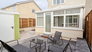 A patio area with outdoor seating and a sliding glass door leading to a covered space. - 17 Third Avenue (Prestatyn)