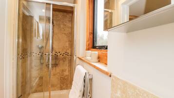 A modern bathroom with a glass-enclosed shower, a bathtub, and a vanity with a mirror.