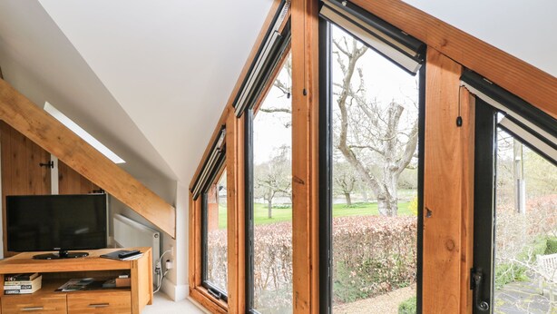 Quarto moderno com um amplo claraboia, móveis de entretenimento em madeira e vista para um jardim.