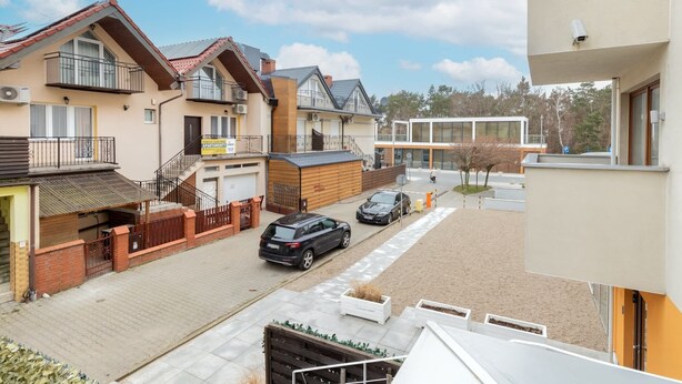 Área residencial com casas, rua pavimentada e um edifício moderno com grandes janelas.