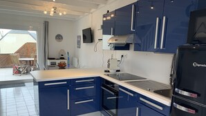 Una cocina moderna con armarios azules, un refrigerador negro y un horno empotrado.