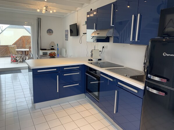 A modern kitchen with blue cabinets, a black refrigerator, and a built-in oven.