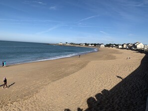 A wide sandy beach with a clear blue sky and calm sea.