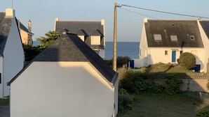 Zona residencial costera con casas de tejados inclinados y el mar a la vista.