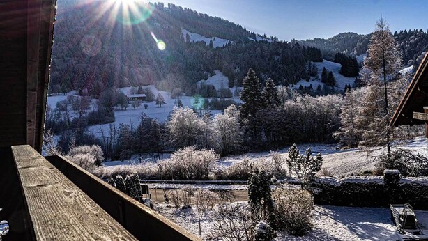 A wooden deck overlooking a snowy landscape with a cabin and trees. - Großzügige Wohnung für bis zu 5 Persone in Steibis (Oberstaufen)