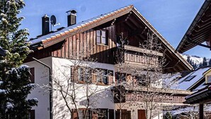 A two-story wooden house with a sloped roof, a covered porch, and a brick driveway. - Großzügige Wohnung für bis zu 5 Persone in Steibis (Oberstaufen)