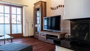 A living room with a television, wooden cabinet, and a fireplace. - Großzügige Wohnung für bis zu 5 Persone in Steibis (Oberstaufen)